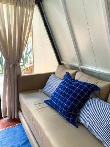 a couch with blue pillows sitting in front of a window at Salto Suizo Parque Ecologico in Independencia