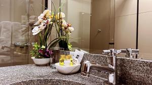 a bathroom sink with a vase of flowers in it at Pacifico Apart Hotel in Santa Cruz de la Sierra