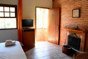 ein Schlafzimmer mit einem Kamin, einem Bett und einem TV in der Unterkunft Refúgio dos Pássaros in Santo Antônio do Pinhal