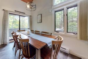 a dining room with a wooden table and some windows at Loon Mountain Getaway in Lincoln