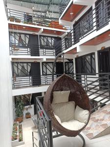einen hängenden Rattansessel auf dem Balkon eines Gebäudes in der Unterkunft Hotel SAMAI in San Agustín