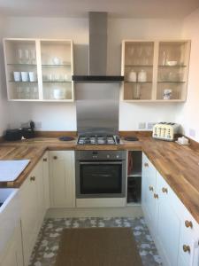 a kitchen with white cabinets and a stove at Rose Cottage, Newbiggin-by-the-Sea in Woodhorn