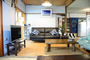 sala de estar con sofá de cuero y mesa en Accommodation Limited to One Group Per Day Yukuiru, en Isla Miyako