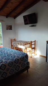 a bedroom with a bed and a table and a television at cabañas La Victoria in La Falda