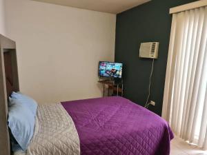 a bedroom with a purple bed and a television at Contry La Silla Apartments zona tec - Nuevo Sur in Monterrey