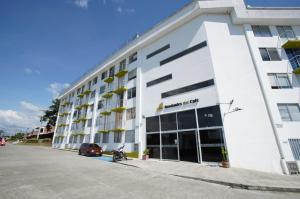 a white building with a motorcycle parked in front of it at Apartamento a 2km del Parque del Café in Montenegro