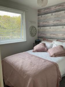 a bedroom with a bed with pink pillows and a clock at MOEL SIABOD - GLAN GWNA HOLIDAY PARK in Caernarfon