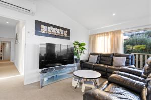 a living room with a couch and a large tv at Alpine Home with Amazing Mountain & Lake Views in Queenstown
