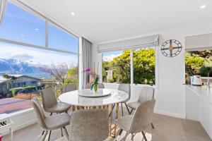 a dining room with a table and chairs and a large window at Alpine Home with Amazing Mountain & Lake Views in Queenstown