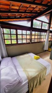 a large bed in a room with windows at Hostel Lagoa do Sol in Saquarema