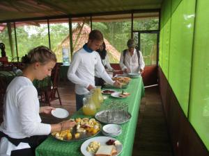 un grupo de personas de pie alrededor de una mesa con comida en Amazon Jaguar Adventure & Lodge, en Iquitos