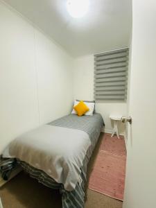 a bedroom with a bed with a yellow pillow on it at Departamento Portal Caldera in Caldera +5 photos