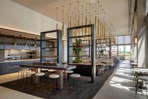 a restaurant with a bar with stools and tables at Hyatt Place Melbourne Caribbean Park in Scoresby