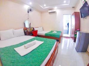 Habitación con 2 camas y manta verde. en Kinh Bac Hotel Quy Nhon, en Quy Nhon