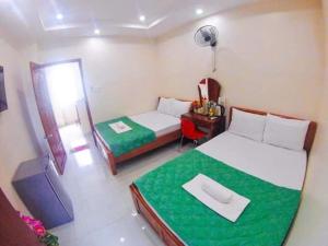1 dormitorio con 2 camas y escritorio con espejo en Kinh Bac Hotel Quy Nhon, en Quy Nhon