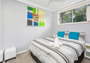 1 dormitorio blanco con 1 cama grande con almohadas azules en CVU Kiama en Kiama