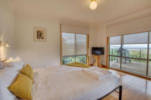 1 dormitorio con cama y ventana grande en Lazy Wave Beach House, en Binalong Bay