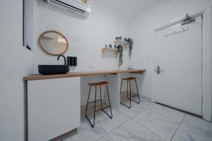 a dressing table in a white room with a mirror and stools at Cozy M Hostel in Sydney