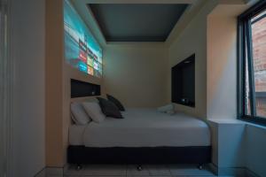 a bedroom with a large bed with a tv on the wall at Cozy M Hotel in Sydney
