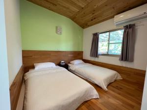 Habitación con 2 camas, paredes verdes y suelo de madera. en 樂樂茶民宿, en Yung-an-ts'un