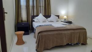 ein Schlafzimmer mit einem großen Bett mit weißer Bettwäsche und Kissen in der Unterkunft Athrakkattu Enclave in Thiruvananthapuram
