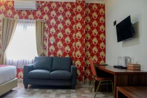 a living room with a blue couch and a red wall at Edotel Manggala Syariah RedPartner in Sudimara