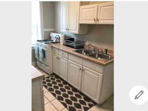 a kitchen with white cabinets and a sink and a stove at Cherry Street Vintage Apartment-Free Parking! in Tulsa