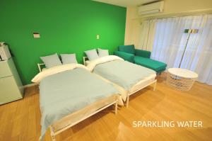 two beds in a room with a green wall at Maison Milano Nakatsu Apartment in Osaka