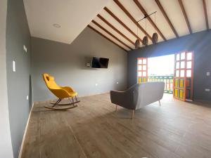 a living room with a yellow chair and a couch at Balcones de la pradera by Hope in Guatapé
