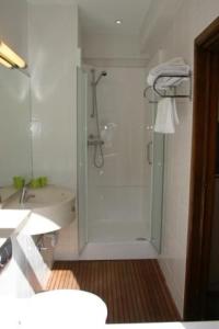 baño blanco con ducha y lavamanos en Hotel Escapade, en De Haan