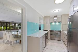 a kitchen with white cabinets and a table with chairs at Sandcastles in Budgewoi