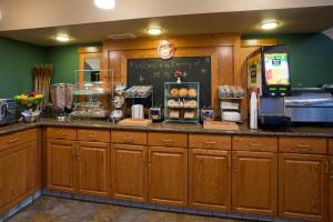 cocina con armarios de madera y encimera con nevera en AmericInn by Wyndham Thief River Falls, en Thief River Falls