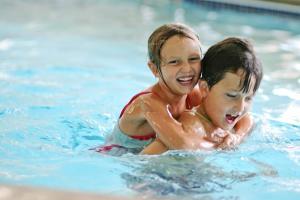 a young girl and a young boy in a swimming pool at AmericInn by Wyndham Thief River Falls in Thief River Falls