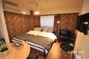 een slaapkamer met een bed en een bakstenen muur bij Maison Milano Nakatsu Apartment in Osaka