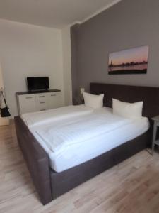 een slaapkamer met een groot bed met witte lakens bij Waldemar-Appartement in Rostock