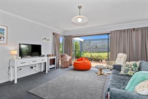 a living room with a couch and a tv at Ruakaka River Retreat - Ruakaka Holiday Home in Ruakaka