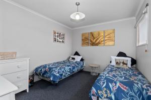 a bedroom with two beds and a dresser at Ruakaka River Retreat - Ruakaka Holiday Home in Ruakaka