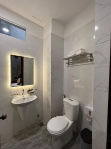 a white bathroom with a toilet and a sink at Happyhomes Saigon Central in Ho Chi Minh City