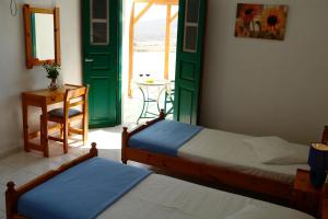two beds in a room with a door and a table at Irene Rooms in Chora Folegandros +43 photos