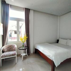 um quarto com uma cama, uma cadeira e uma janela em Phuong Vy 2 em Da Lat