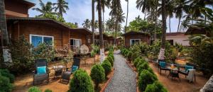 a garden with tables and chairs in front of a house at Mariners Bay Beach Resort in Arambol