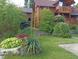 a log house with a garden in front of it at Котедж "Хата Рибака" in Kosiv