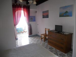 a bedroom with a bed and a dresser with a television on it at Appartamenti Iacono in Forio d'Ischia