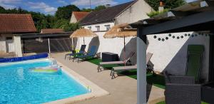 uma piscina com cadeiras e guarda-sóis num quintal em LE BON’HEURE em Abilly-Sur-Claise