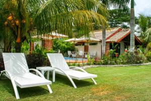 two white chairs sitting in the grass in front of a house at Burudika Bungalows in Selong Belanak
