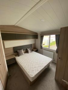 a large bed in a room with a window at 17 Wildflower Meadow in Chapel Saint Leonards