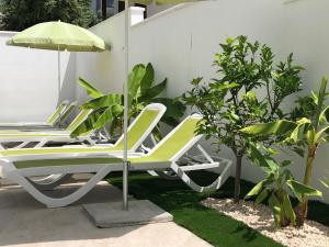 two lounge chairs and an umbrella on a patio at Diklo beach rooms-Adults Only in Zadar