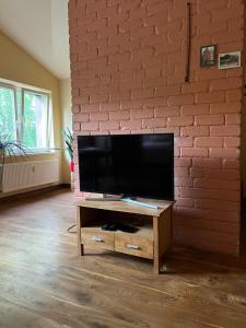 a flat screen tv on a wooden stand in front of a brick wall at Apartamentai Palangos Centre in Palanga