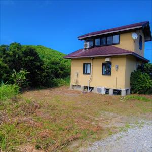 żółty dom na szczycie trawiastego wzgórza w obiekcie koco w mieście Nishinoomote