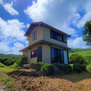 una casa en la cima de una colina con un cielo en koco, en Nishinoomote